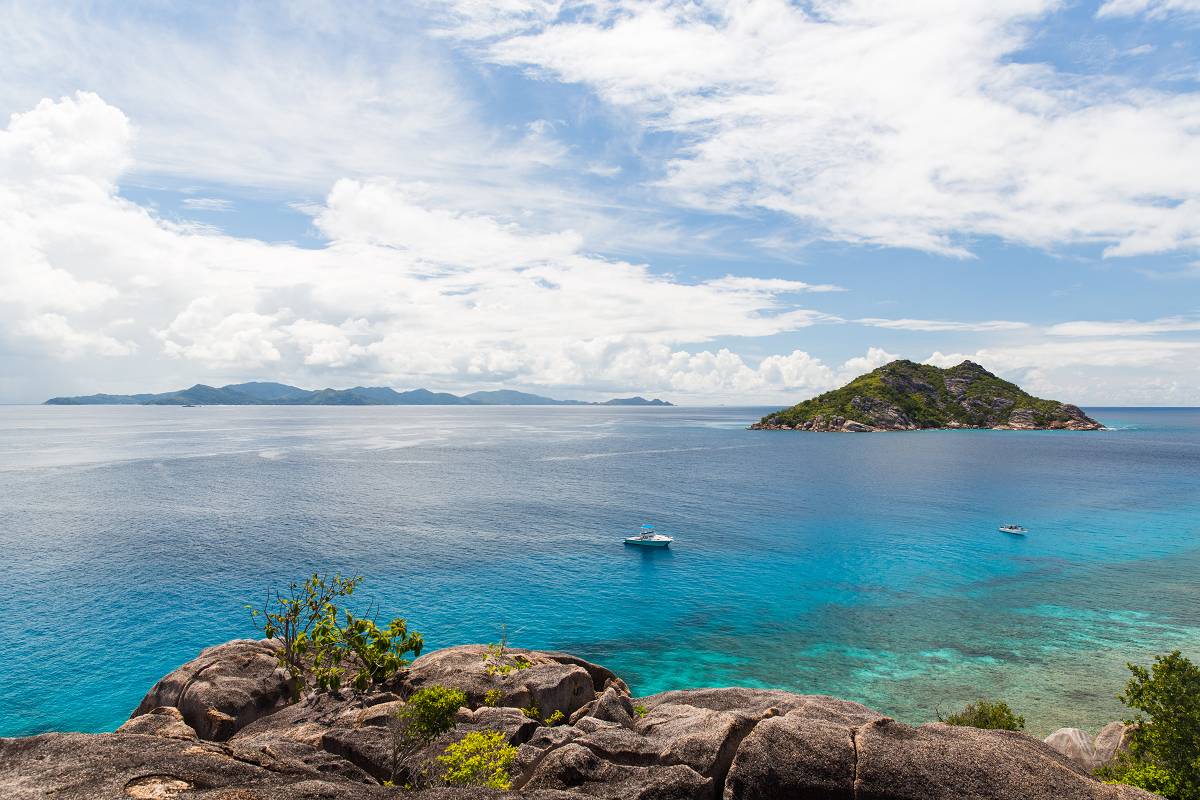Two boats are anchored in beautiful blue water among tropical islands